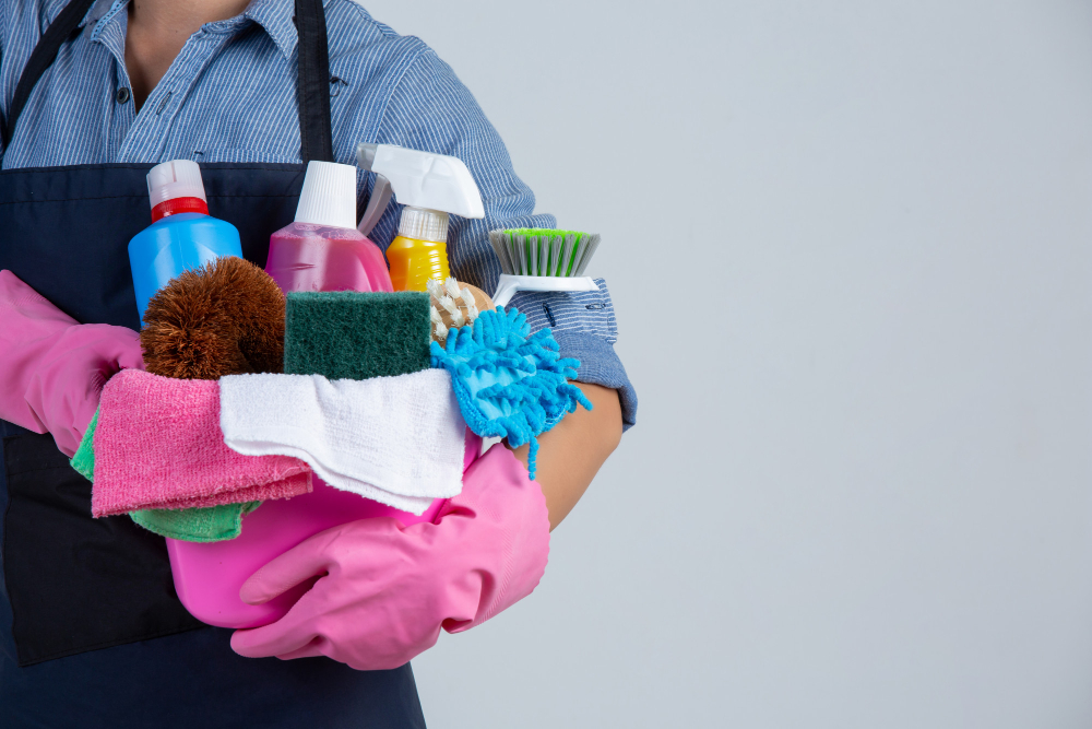 A cleaner holding an armful of cleaning supplies and fresh towels